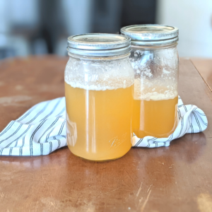 two wide mouth jars of chicken bone broth made in the instant pot on a farmhouse table