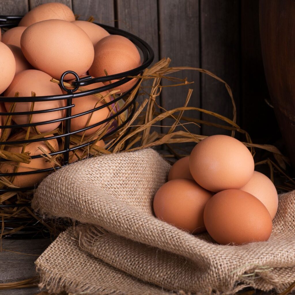 brown chicken eggs in an egg basket and some are on burlap