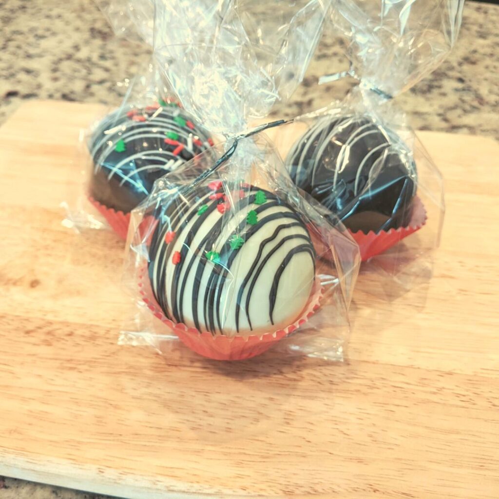 Hot chocolate bombs in cup cake liners in cellophane bags on top of a wooden cutting board